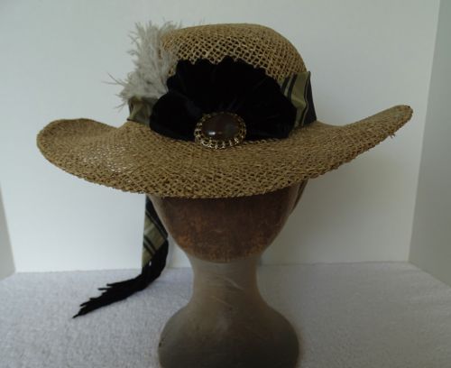 Another front view of the hat with feather, hat band, cockade, and trailing ends seen.